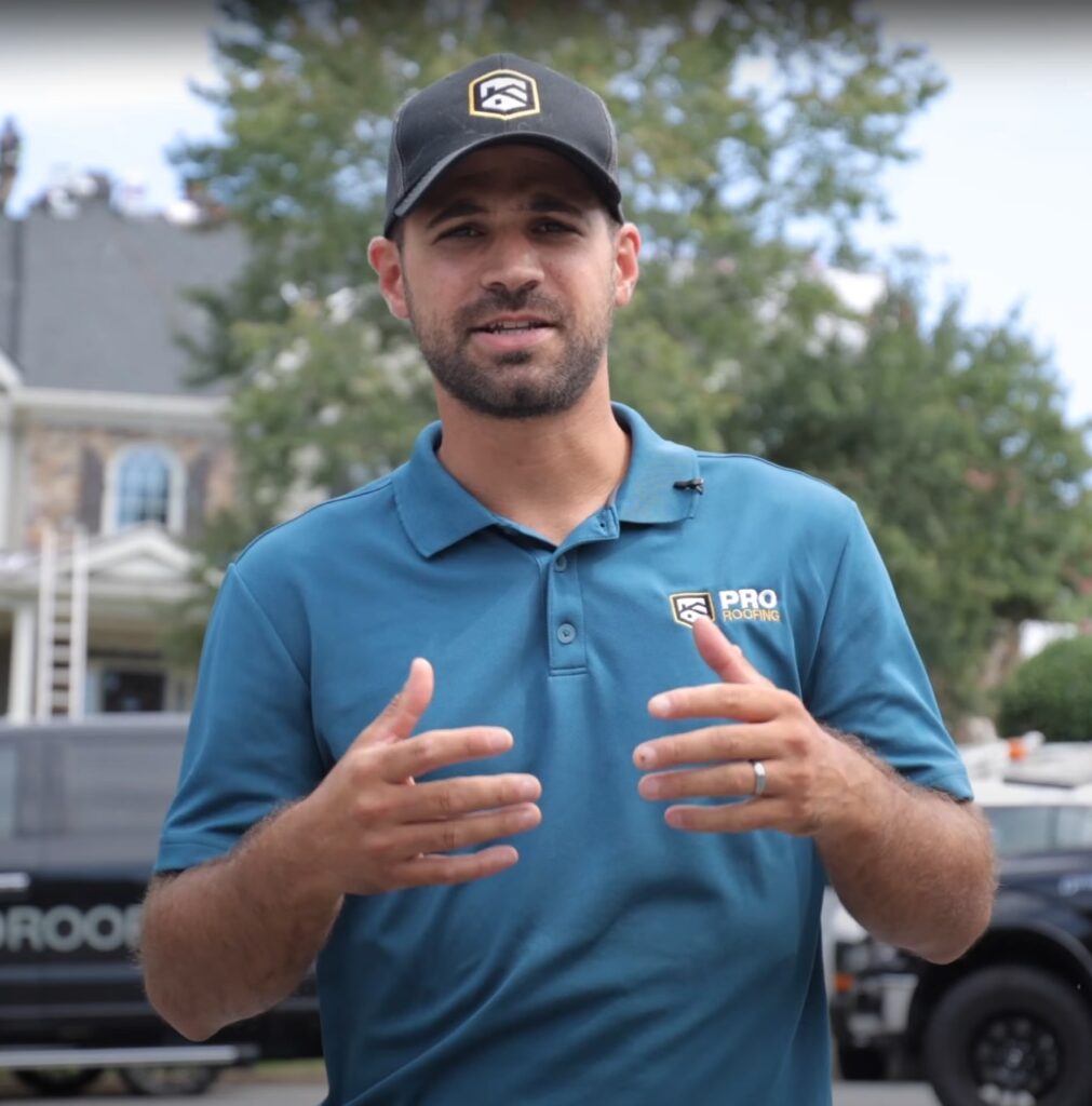 ProRoofing Team member helping explain roofing insurance claims in a blue polo shirt